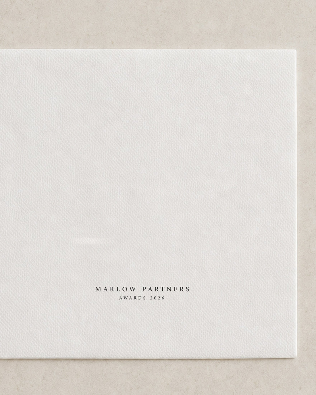 Folded white cocktail napkin printed in black with an awards night mark, an example brand
