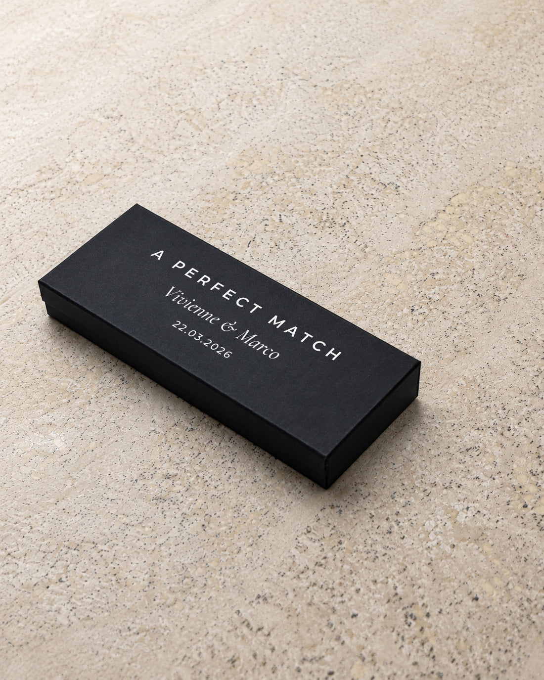 Ember slim matchbox in black, closed at an angle on stone