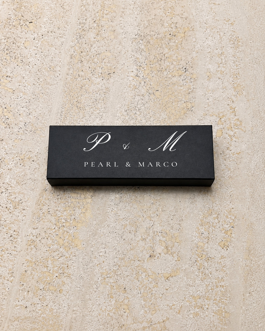 Pearl slim matchbox in black, closed on stone