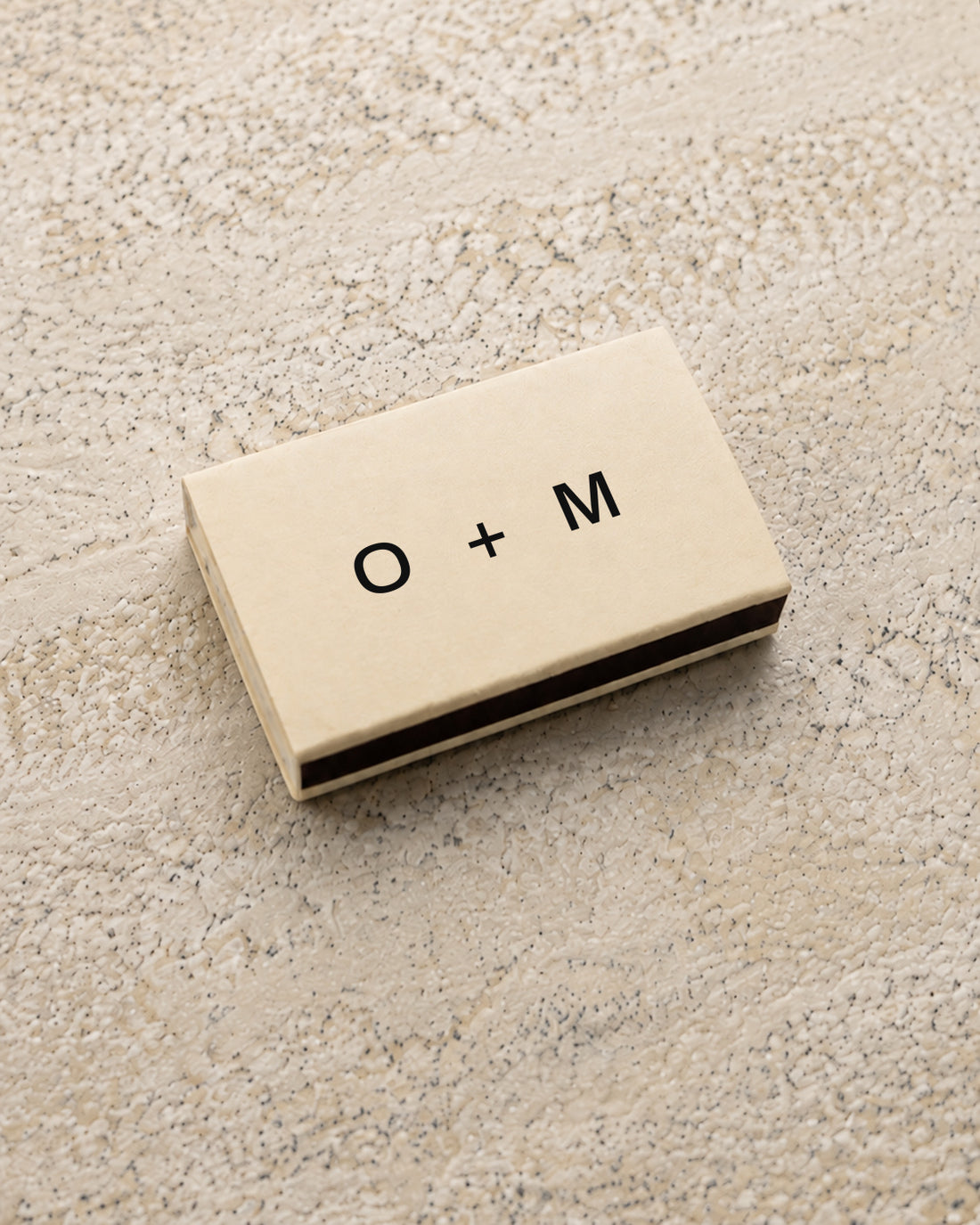 Emblem classic matchbox in ivory, closed at an angle on stone