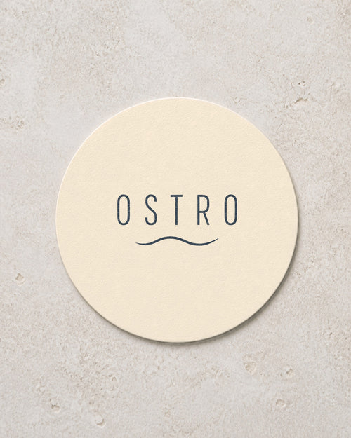 Round ivory coaster printed with a navy bar wordmark, an example brand