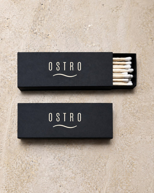 Two black slim matchboxes printed with an ivory bar wordmark, one tray open, an example brand
