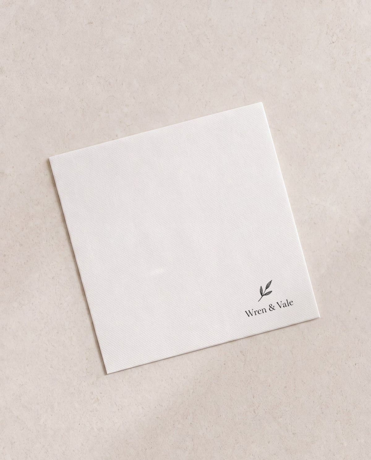 Folded white cocktail napkin printed in black with a small winery mark in the corner, an example brand