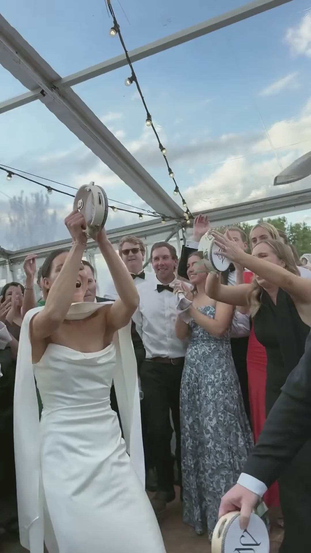 A bride and groom raising personalised Solene wedding tambourines at their reception